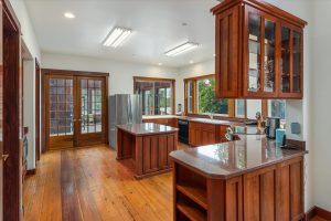Custom cherry wood cabinets and a walk-in pantry (not visible) provide massive storage in this efficient space. The counters and center island are topped with granite, with a large butcher block section next to the refrigerator. The fig tree outside the kitchen window is the center of activity for all the wildlife, especially during the summer, providing endless interest and entertainment while cooking or cleaning up. Double doors lead in to the solarium. Close them in summer to keep the house cool, open in winter to let in the heat.