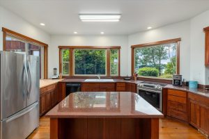 Custom cherry wood cabinets and a walk-in pantry (not visible) provide massive storage in this efficient space. The counters and center island are topped with granite, with a large butcher block section next to the refrigerator. The fig tree outside the kitchen window is the center of activity for all the wildlife, especially during the summer, providing endless interest and entertainment while cooking or cleaning up. Double doors lead in to the solarium. Close them in summer to keep the house cool, open in winter to let in the heat.