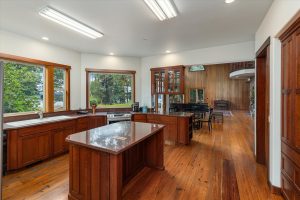 Custom cherry wood cabinets and a walk-in pantry (not visible) provide massive storage in this efficient space. The counters and center island are topped with granite, with a large butcher block section next to the refrigerator. The fig tree outside the kitchen window is the center of activity for all the wildlife, especially during the summer, providing endless interest and entertainment while cooking or cleaning up. Double doors lead in to the solarium. Close them in summer to keep the house cool, open in winter to let in the heat.