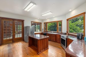 Kitchen features marble counters, center island with marble counter, double doors to solarium and pass-through window over wood chopping block.