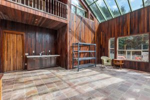 Solarium showing door to middle garage bay, sink and counter, easy-care slate floor and redwood siding. Windows face the garden.