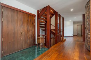 Custom built stairways lead from the main entry hall to the upper and lower levels, located behind the Great Room's Russian Fireplace. Facing the south, this end of the hall leads to the main entry on the left, just before the stairwell, the media room on the left at the end and terminating in the powder room