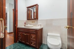 Powder Room at the south end of the main hall, adjoining the mud room and right next to the Media Room. Cherry cabinet topped with a marble counter.
