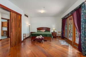 The Master Bedroom includes a sleeping area, double-doors leading to the hallway across from laundry room, a sliding door leading to a deck off the bedroom, plus a sitting area and Swedish-style masonry brick heater.