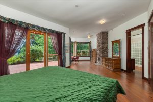 View from master bedroom sleeping area toward the outside deck, inside sitting area, masonry brick heater and entry to master bath