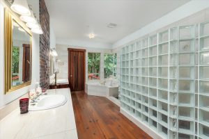 The Master Bath enters both the Master Bedroom and master closet. It features double sink counters, marble soaking tub overlooking both the side lawn and woods toward the water, and glass block enclosed shower with marble walls, tile floor and two shower spigots.