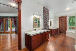 Master bathroom showing door leading from bedroom, double sink counters, door to outside deck and corner of marble tub