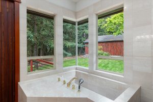 Marble soaking tub in master bathroom overlooking the side yard and woods
