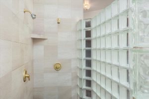 Glass block enclosed shower in master bathroom, with marble tiled walls and double shower spigots