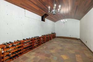 The landing area at the foot of the stairway leading to the bottom level leads to the highly coveted wine cellar. (The owners also used it as a root cellar to store produce from the orchard and garden or to keep other things cool, such as coffee beans, extra herbs and spices, essential oils, etc.) Redwood entry door and barrel ceiling with two chandeliers provide ambience. It was designed with room for a table and chairs for wine tastings. Below ground, the temperature maintains around 55 degrees, perfect for wine storage.