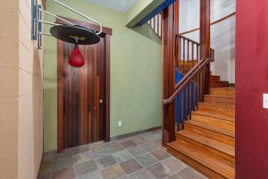 Landing area at the bottom of the stairwell leading down from the main floor, facing the door to a mechanical room