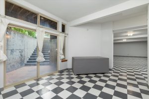Finished basement level facing north, showing the sliding doors and stairway leading to the patio and decks on main level