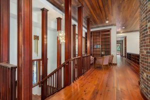 Upper hall showing long leaf yellow southern pine floor, redwood ceiling, library shelves and nook, and stairwell to main floor