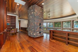 The brick structure housing the baffles inside the Russian Fireplace continue through the second level up to the chimney in the roof. In front of the brick is a cozy sitting area with a fabulous view through the Great Room windows toward Puget Sound and Gig Harbor.