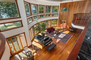 From the upper hall is a sweeping view of outside and the Great Room below. The black marble counter along the hall provides safety with more shelves below it.