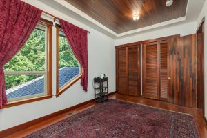 The first upstairs bedroom has windows overlooking the driveway and woods to the east. Handmade slatted wood doors provide ventilation to the ample closets.
