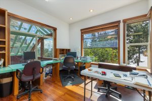 Main office with windows overlooking the front yard and Puget Sound, as well as a sliding window opening over the solarium, with shelves, counters and corner computer station