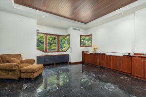 This room used as a second executive office faces north, with a window looking out toward the side lawn, shops and back field. The house plans all are stacked on top of the built-in shelves for the Buyer's review. The counter has a small sink, and plumbing was installed below the marble floor to leave the possibility for a future en suite second master bedroom.